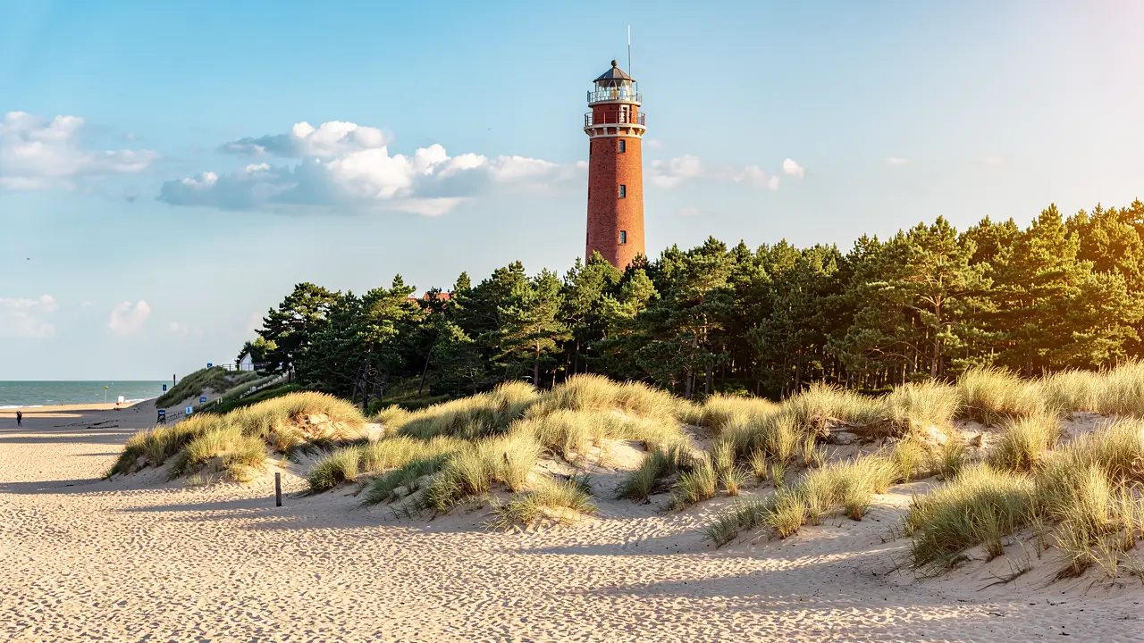 A wide, clean golden Baltic beach at Krynica Morska backed by tall pine-covered dunes under a soft summer sky (illustration)
